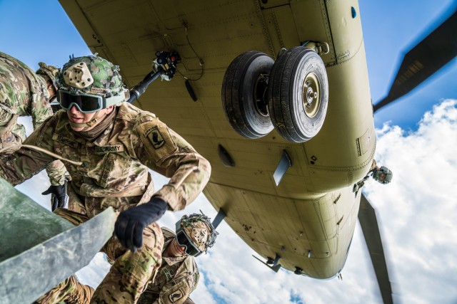 Photo by Maj. Robert Fellingham.

A crew chief with B Co "Big Windy," 1-214th General Support Aviation Battalion relays vital position information back to the CH-47 Chinook pilot from his side window as paratroopers from the 173rd Airborne Brigade hook their pallet of equipment to the underside of the helicopter. (U.S. Army photo by Maj. Robert Fellingham) 