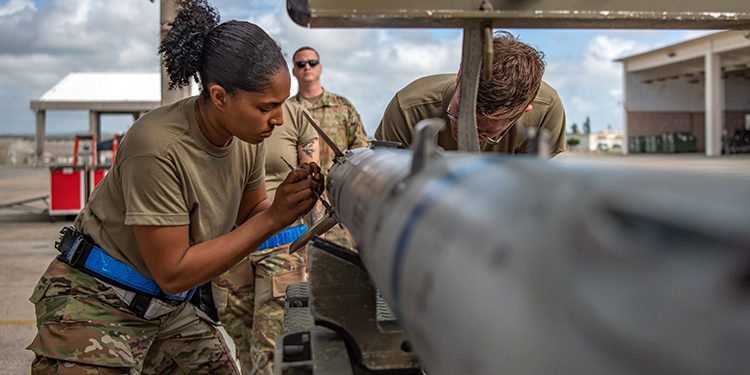 Air Force airmen install wings on an advanced medium-range air-to-air missile during a loading competition at Kadena Air Base, Japan, Nov. 30, 2021. Crews must be proficient in performing approximately 800 critical steps that maintain the safety, security and reliability of weapons systems.